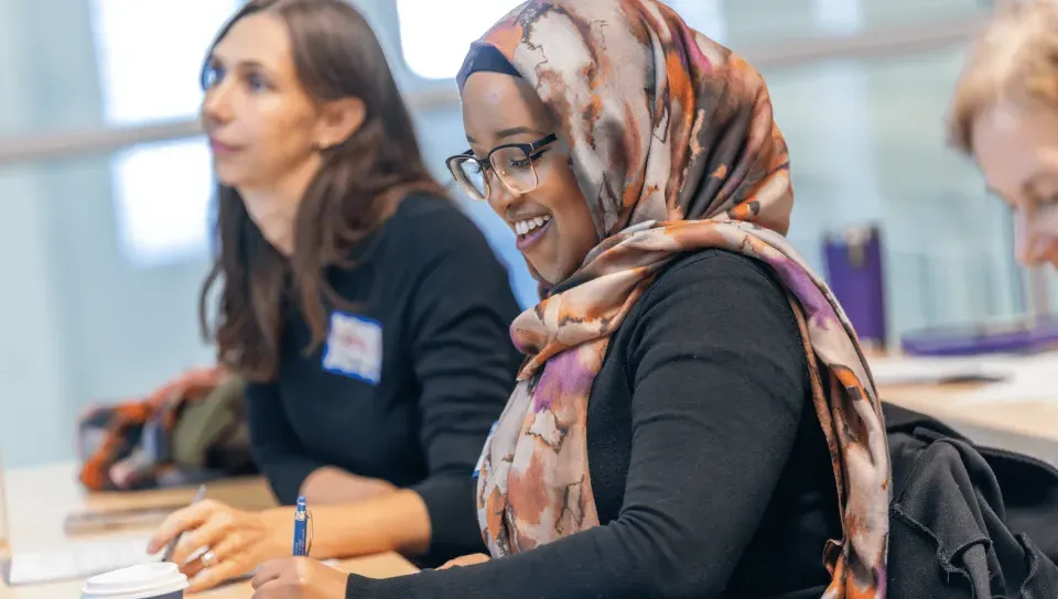 Two female students take notes at a desk